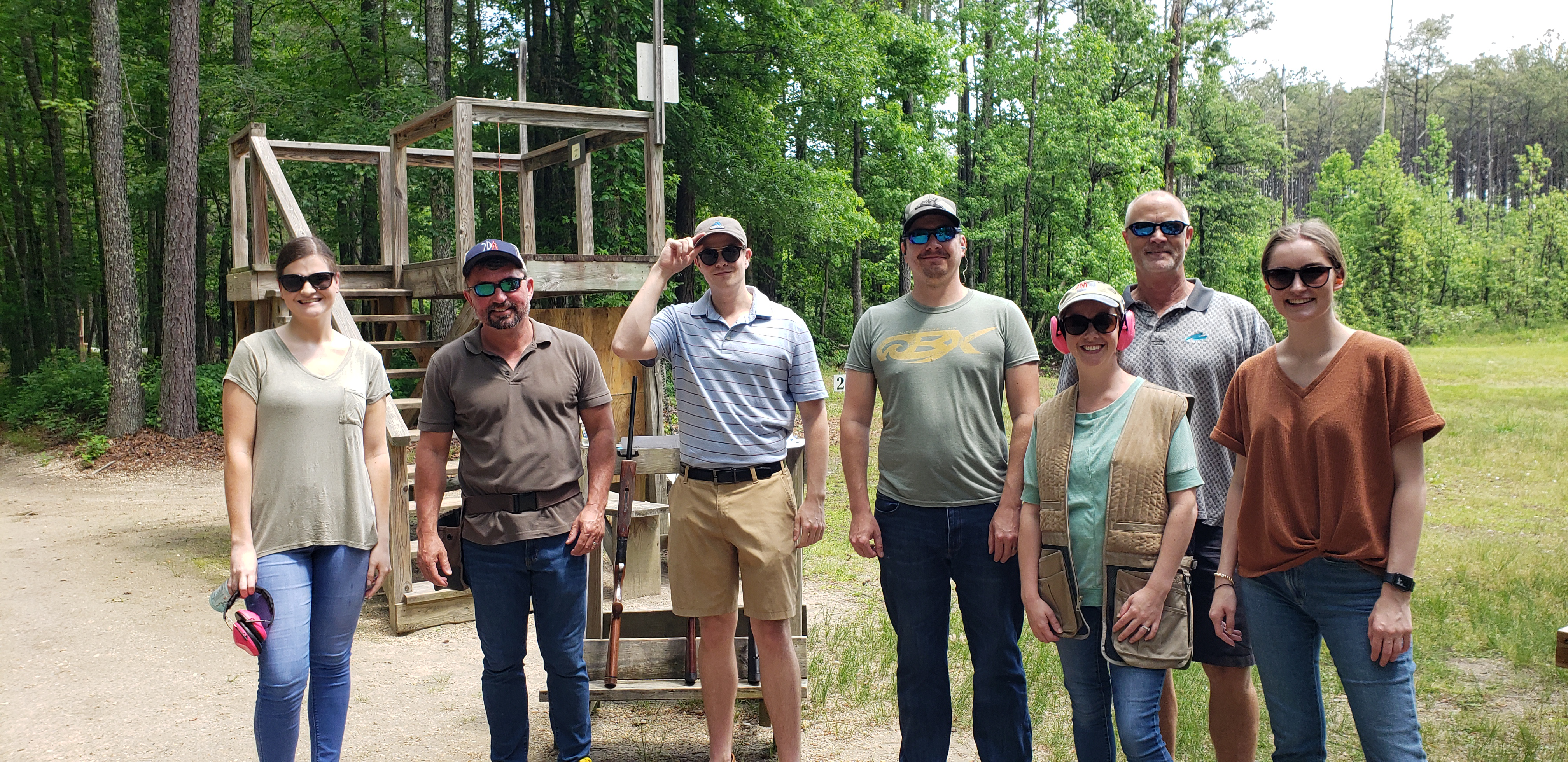 a group of seven people standing in front of a clay shoot stand