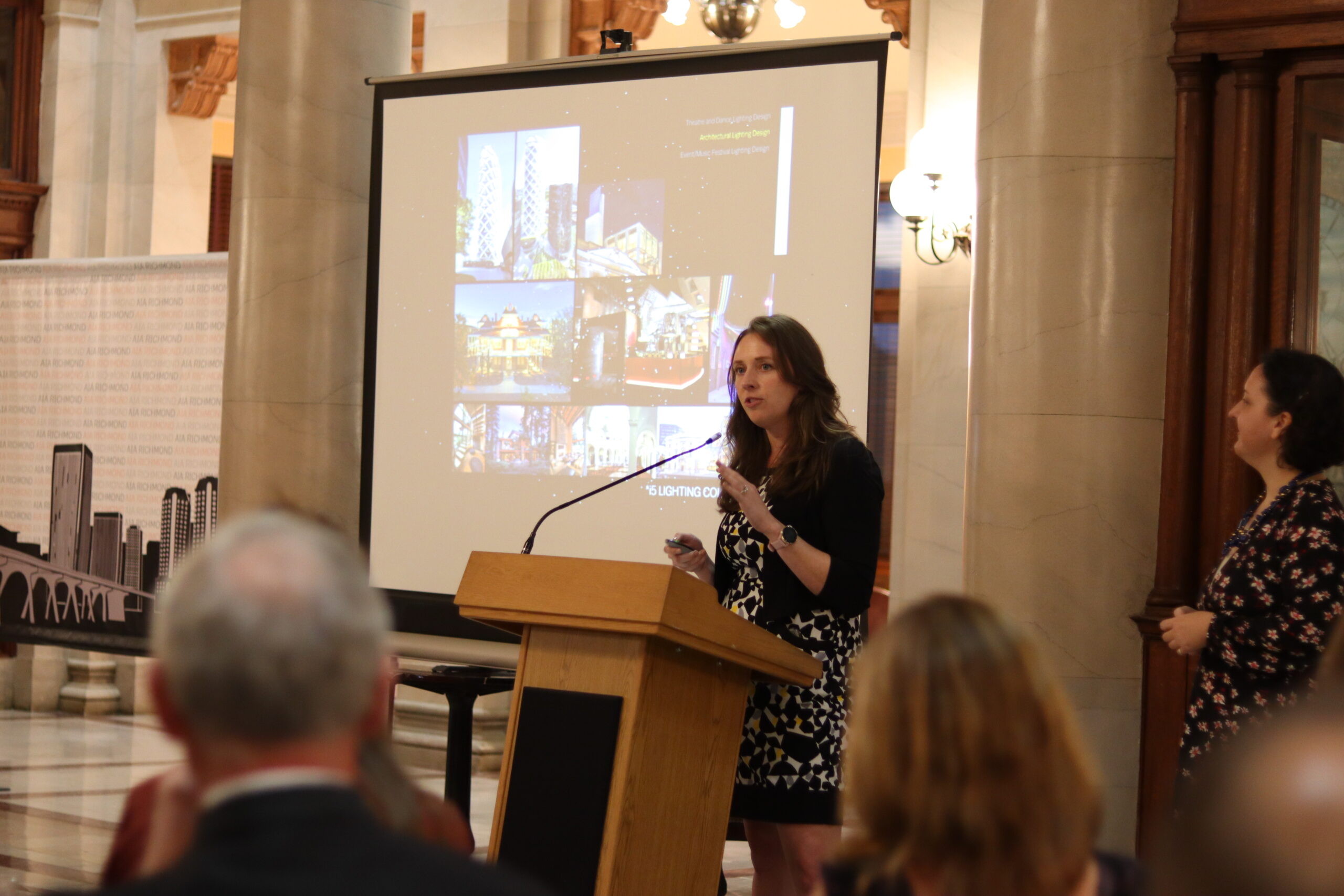 Rachel Shelton making opening remarks at 2021 honors ceremony in the foreground. A screen in the background.